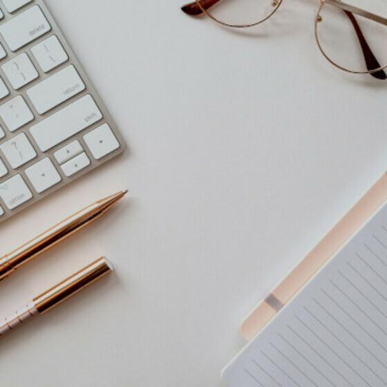 various stationery items with a keyboard and glasses